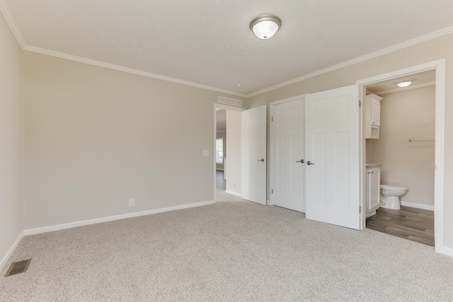 unfurnished bedroom with crown molding, light carpet, and ensuite bath