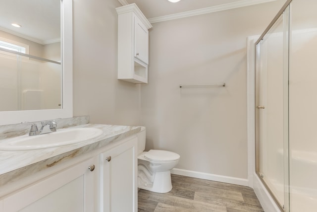 bathroom with hardwood / wood-style floors, vanity, a shower with door, toilet, and ornamental molding