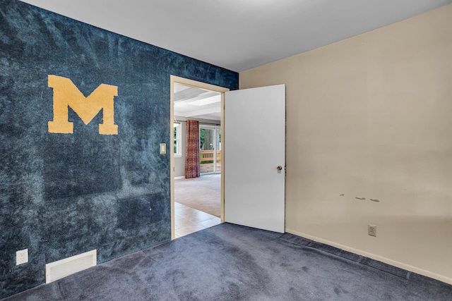 empty room featuring carpet flooring and beamed ceiling