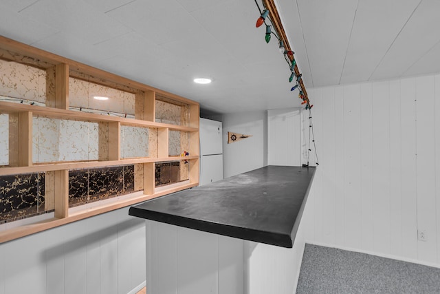 interior space featuring carpet floors, white refrigerator, rail lighting, and wood walls