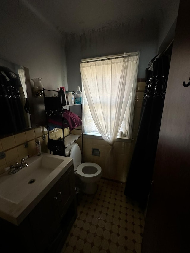 bathroom with vanity, toilet, and tile walls