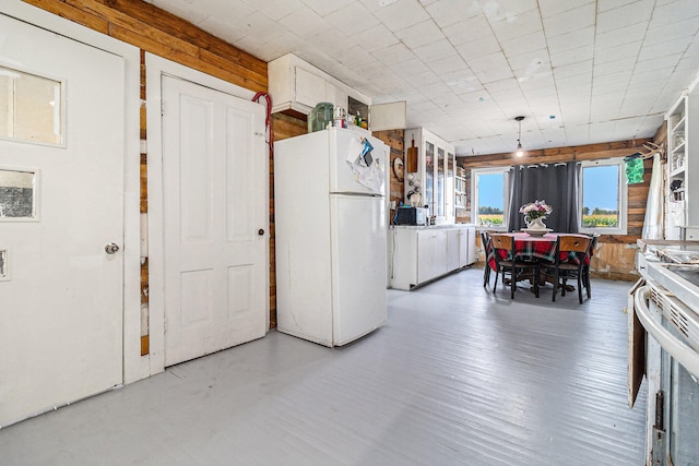 kitchen featuring range, wood walls, white cabinetry, and white refrigerator