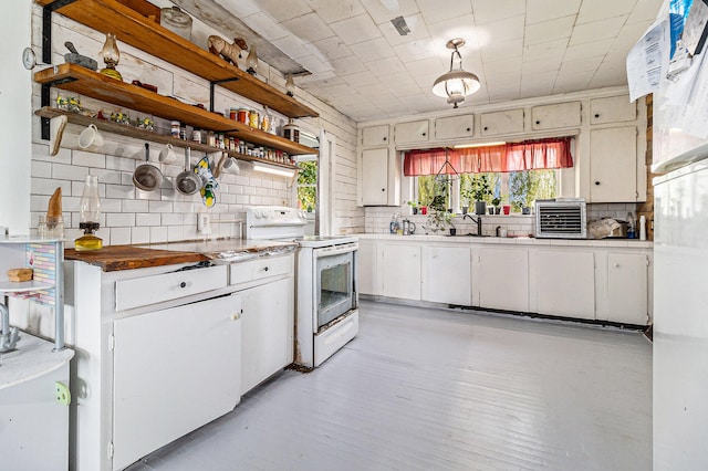 kitchen featuring decorative backsplash, white stove, white cabinetry, and sink