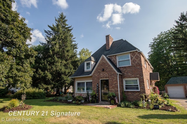 view of front of property featuring a garage, an outbuilding, and a front lawn