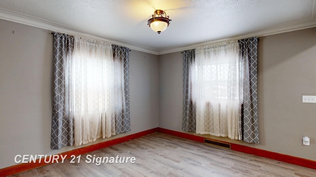 empty room with ornamental molding, hardwood / wood-style floors, and a textured ceiling