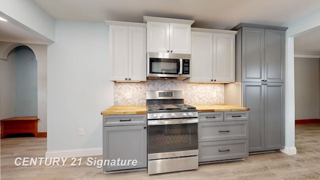 kitchen featuring stainless steel appliances, butcher block counters, backsplash, and light hardwood / wood-style flooring