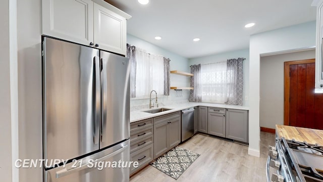 kitchen with appliances with stainless steel finishes, sink, gray cabinetry, and light hardwood / wood-style floors