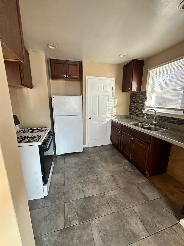 kitchen with freestanding refrigerator, a sink, decorative backsplash, and gas stove