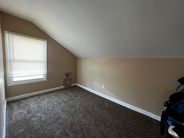 bonus room with dark carpet and vaulted ceiling