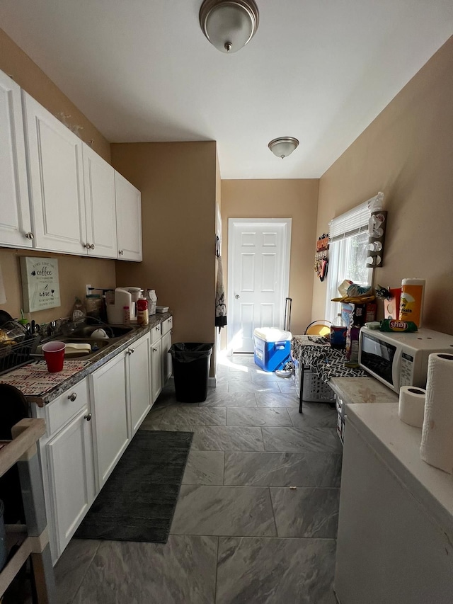 kitchen featuring white cabinetry, dark stone countertops, and sink