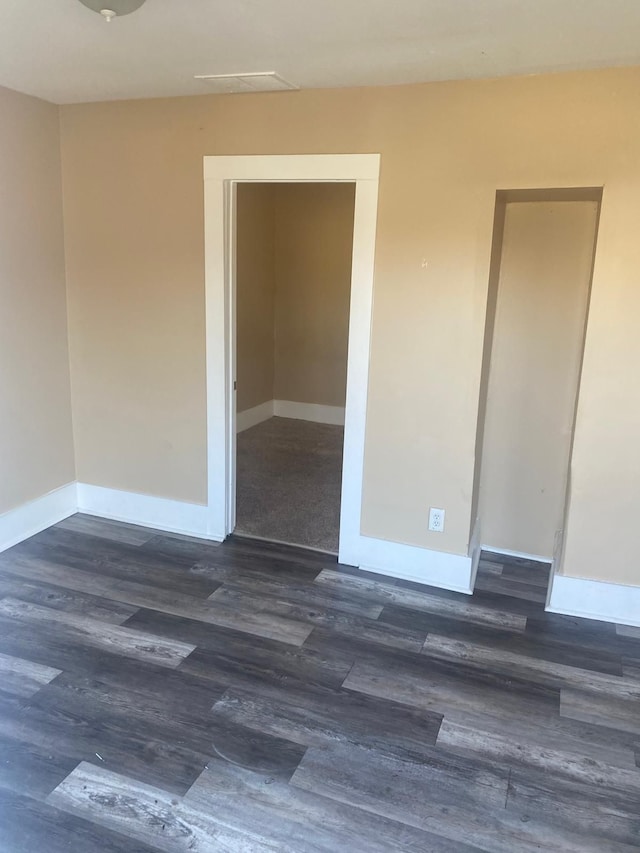 empty room with dark wood finished floors and baseboards