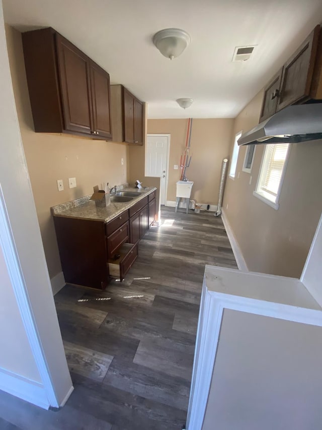 kitchen featuring visible vents, a sink, dark wood finished floors, dark brown cabinetry, and baseboards