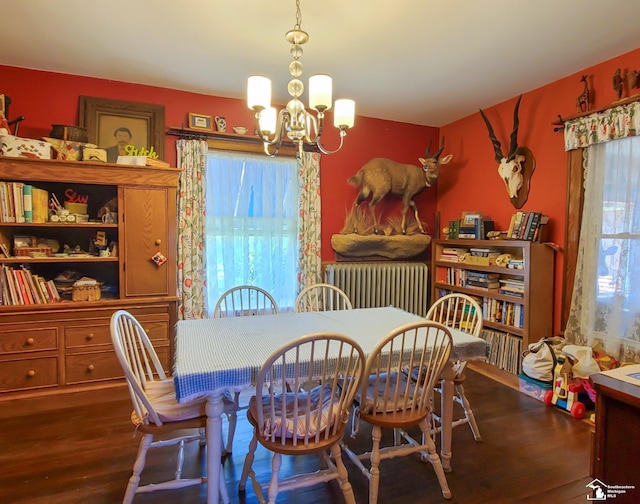 dining room with radiator heating unit, an inviting chandelier, and hardwood / wood-style floors