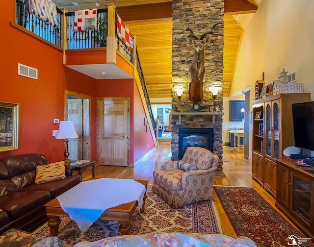 living room featuring light wood-type flooring, a fireplace, and high vaulted ceiling