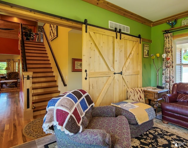 living room with a barn door, plenty of natural light, hardwood / wood-style floors, and ornamental molding