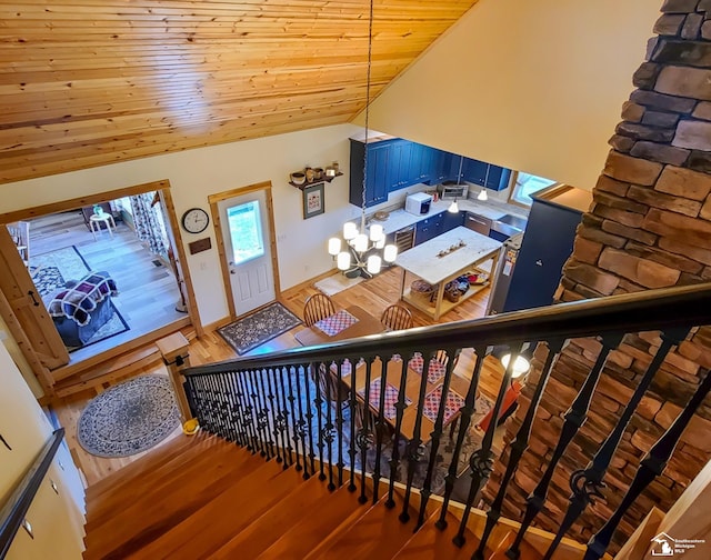 stairway featuring hardwood / wood-style floors, high vaulted ceiling, a notable chandelier, and wood ceiling