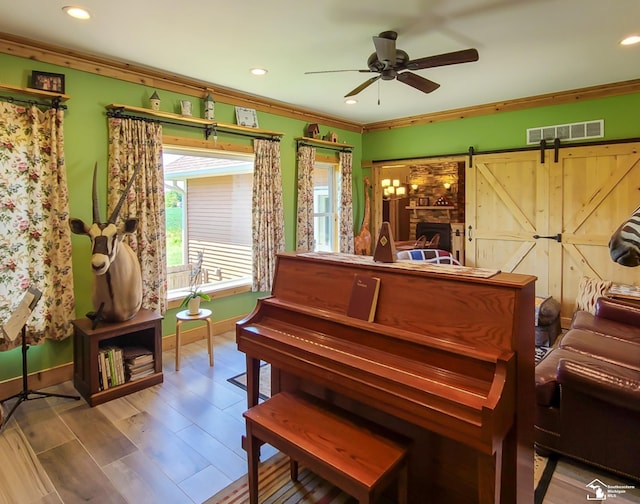 misc room featuring hardwood / wood-style floors, a barn door, ceiling fan, and ornamental molding