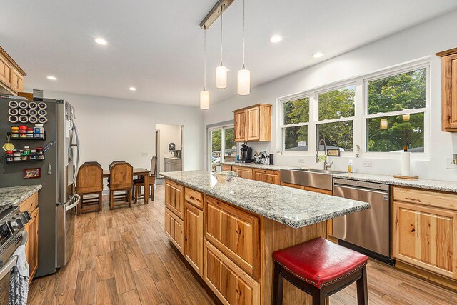 kitchen featuring light stone countertops, hardwood / wood-style floors, a kitchen island, and appliances with stainless steel finishes