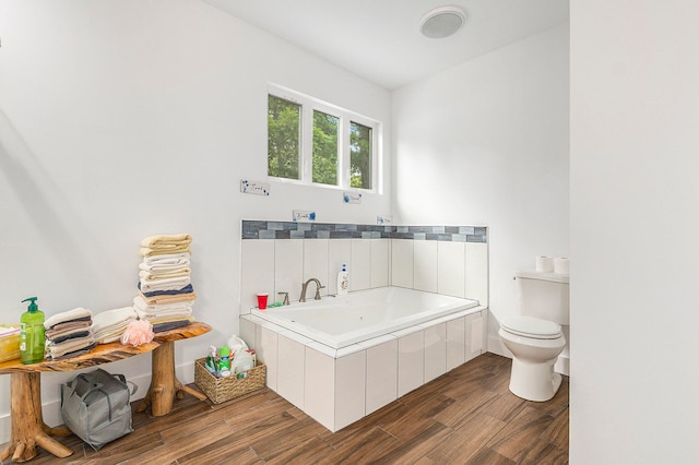 bathroom with hardwood / wood-style flooring, toilet, and a tub