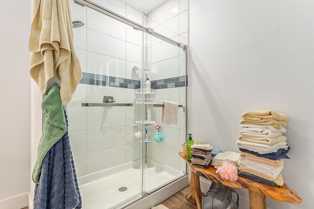 bathroom with hardwood / wood-style floors and a shower with shower door