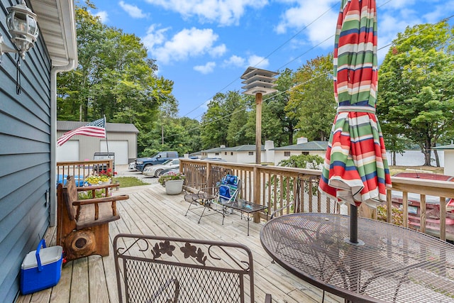 wooden deck featuring a garage and an outbuilding