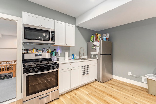 kitchen featuring appliances with stainless steel finishes, white cabinetry, and sink