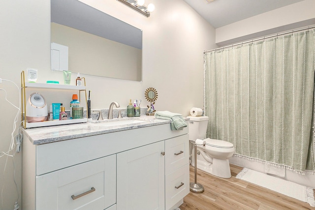 bathroom with wood-type flooring, vanity, toilet, and curtained shower