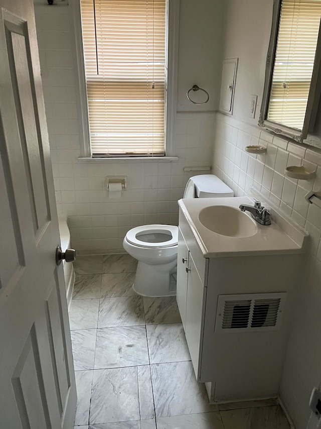 bathroom featuring vanity, tile walls, and toilet