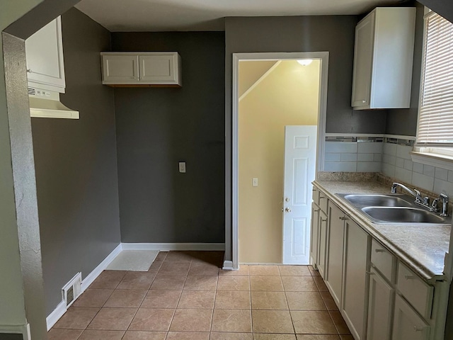 kitchen with tasteful backsplash, ventilation hood, sink, white cabinets, and light tile patterned flooring