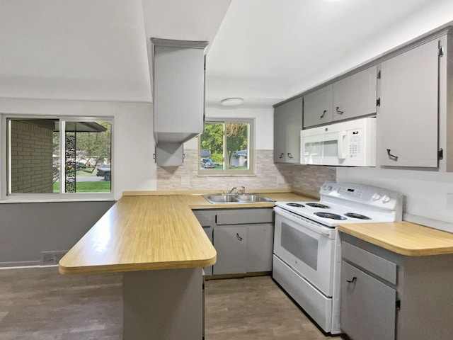 kitchen with white appliances, sink, hardwood / wood-style flooring, gray cabinets, and kitchen peninsula