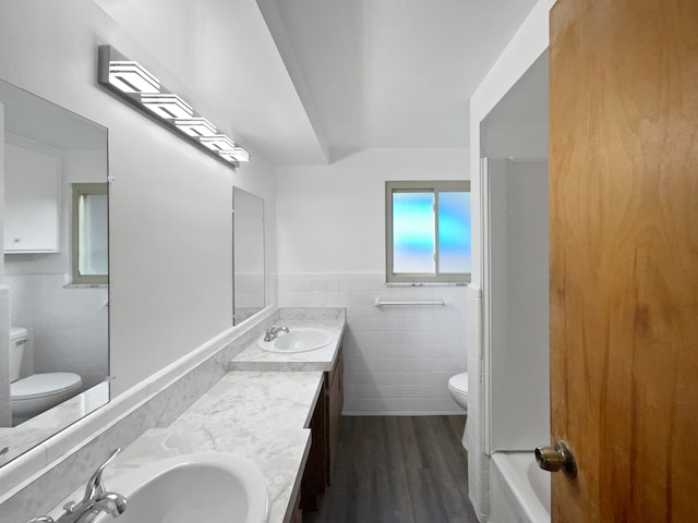 bathroom featuring vanity, hardwood / wood-style flooring, toilet, and tile walls