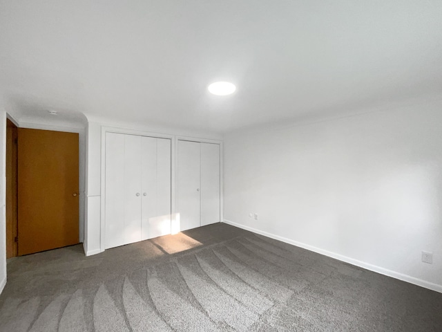 unfurnished bedroom with dark colored carpet and two closets