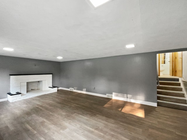 unfurnished living room with hardwood / wood-style floors and a brick fireplace