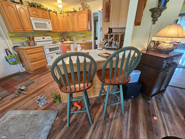 kitchen with dark hardwood / wood-style flooring, white appliances, and backsplash