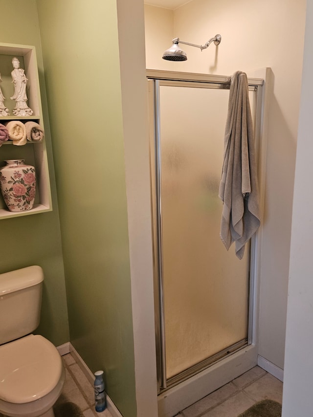 bathroom featuring tile patterned flooring, a shower with shower door, and toilet