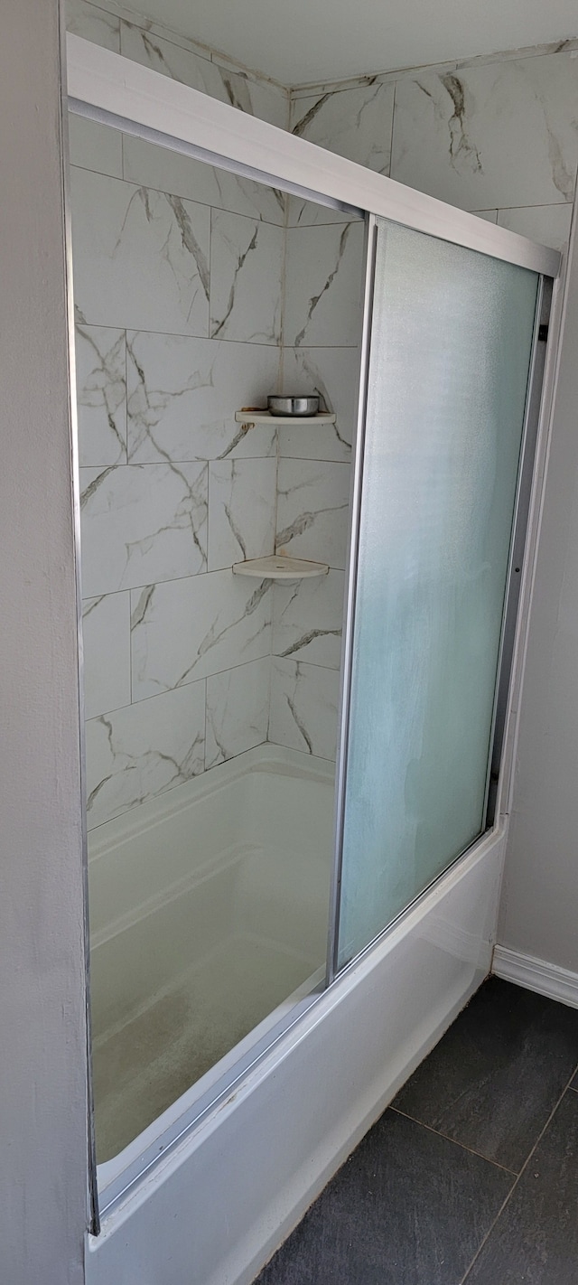 bathroom with tile patterned flooring and bath / shower combo with glass door