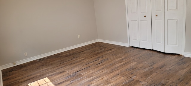 unfurnished bedroom featuring dark hardwood / wood-style flooring and a closet