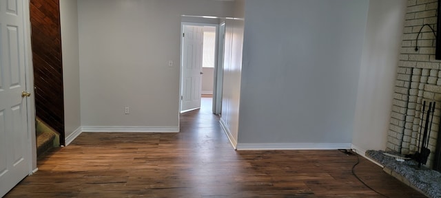 spare room with dark hardwood / wood-style floors and a brick fireplace