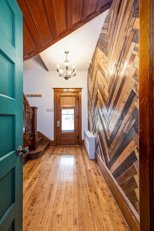 entryway featuring a notable chandelier, wood walls, and light hardwood / wood-style floors