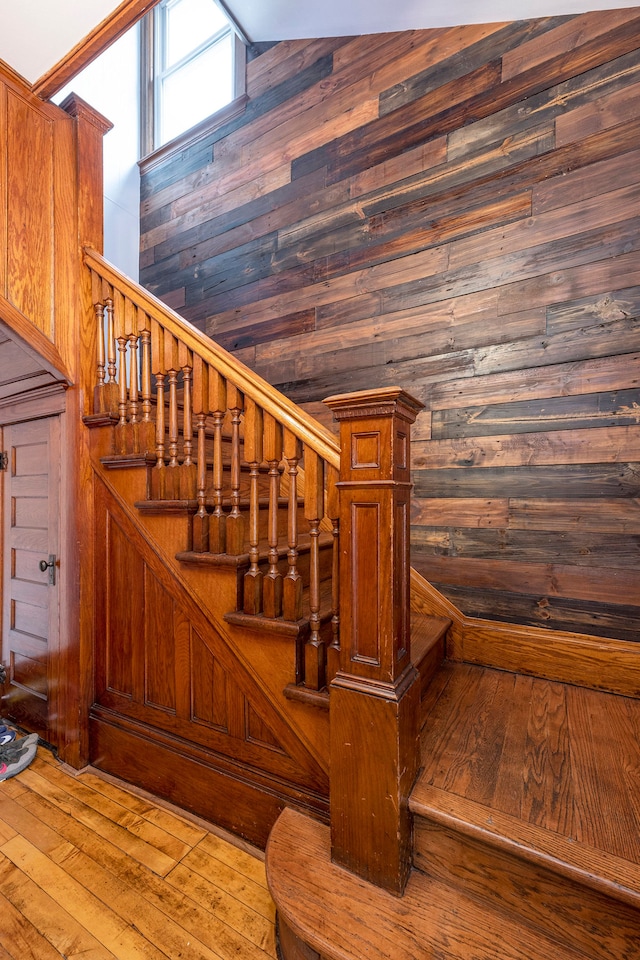 staircase with wood-type flooring, lofted ceiling, and wood walls