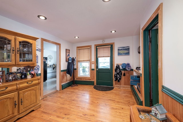 entryway with light wood-type flooring and wooden walls