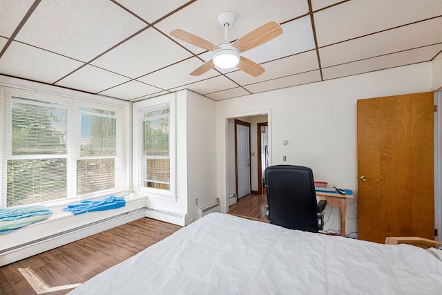 bedroom with ceiling fan, wood-type flooring, and a drop ceiling