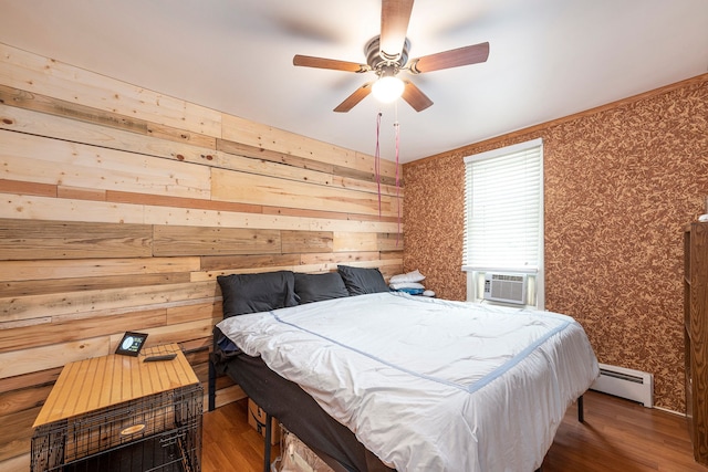 bedroom with wood walls, a baseboard heating unit, ceiling fan, cooling unit, and dark hardwood / wood-style floors