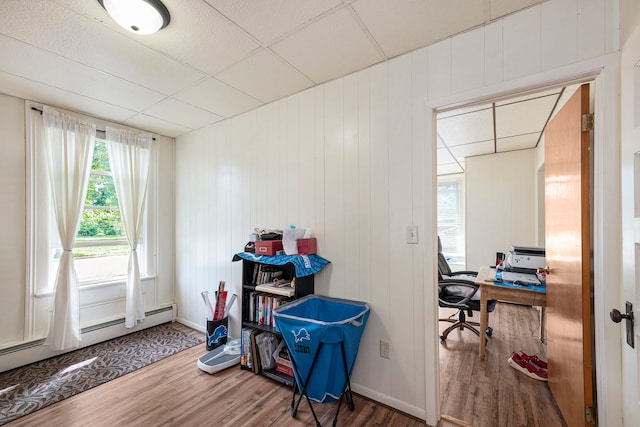 office featuring a paneled ceiling, wooden walls, and hardwood / wood-style flooring