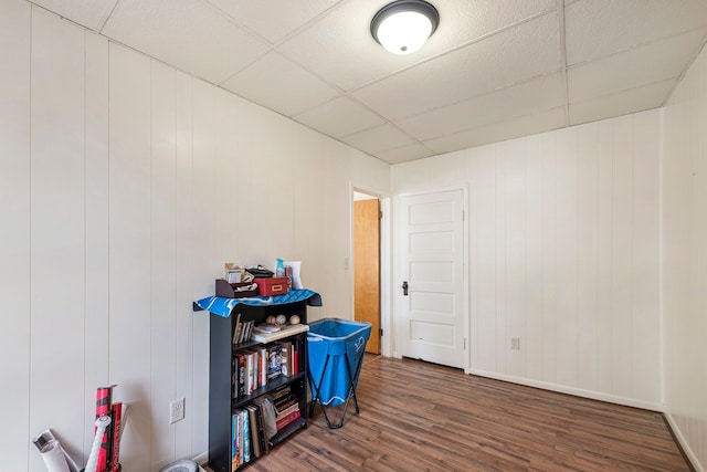 misc room featuring wood walls, a paneled ceiling, and dark hardwood / wood-style floors