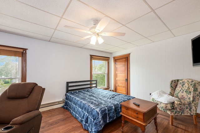 bedroom with ceiling fan, a paneled ceiling, dark hardwood / wood-style floors, and baseboard heating