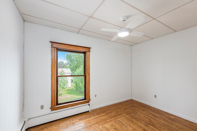 unfurnished room featuring ceiling fan, baseboard heating, a drop ceiling, and wood-type flooring