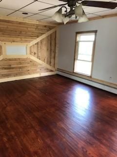 bonus room with ceiling fan, hardwood / wood-style flooring, wooden walls, and a baseboard radiator