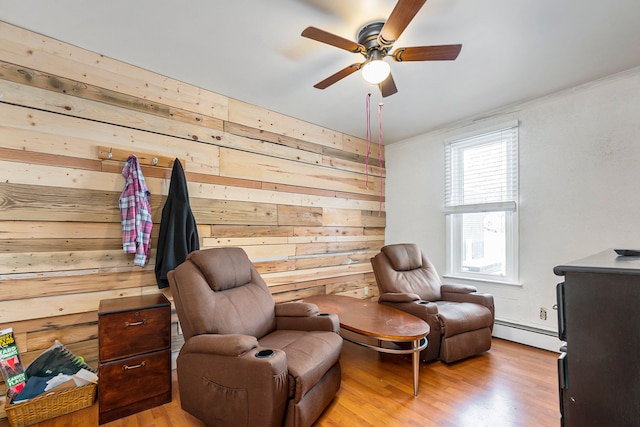 living area featuring ceiling fan, wooden walls, crown molding, light wood-type flooring, and baseboard heating