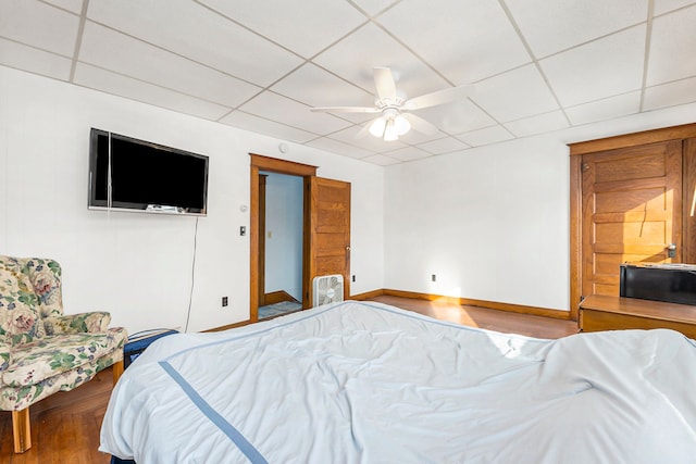 bedroom with ceiling fan, hardwood / wood-style floors, and a paneled ceiling